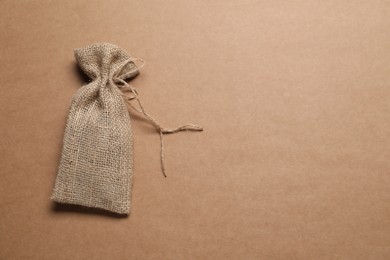 One burlap sack on brown background, top view. Space for text