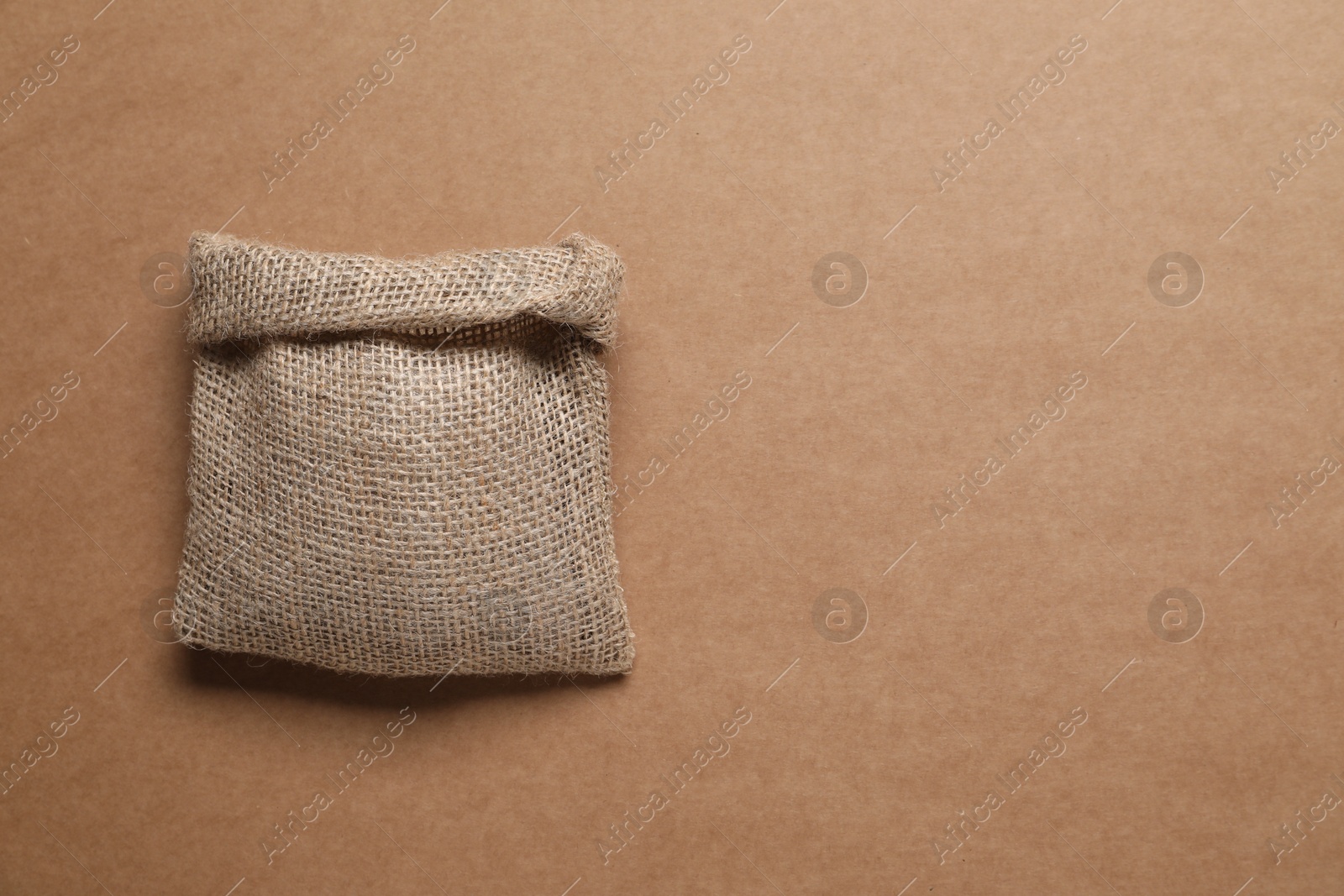 Photo of One burlap sack on brown background, top view. Space for text