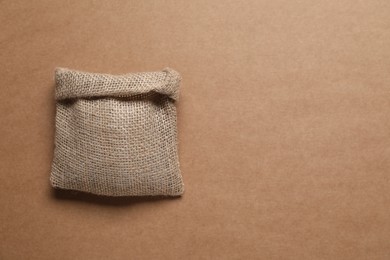 Photo of One burlap sack on brown background, top view. Space for text