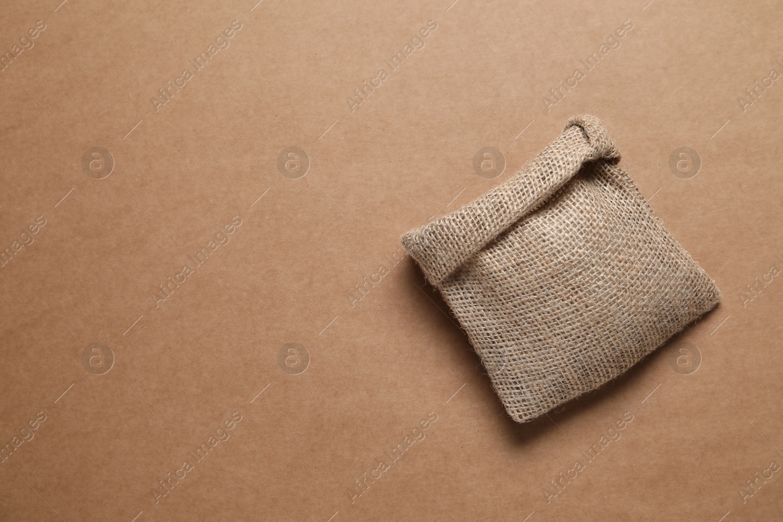 Photo of One burlap sack on brown background, top view. Space for text