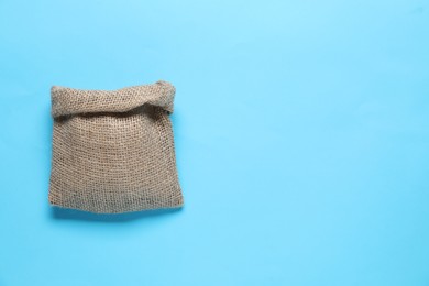 Photo of One burlap sack on light blue background, top view. Space for text