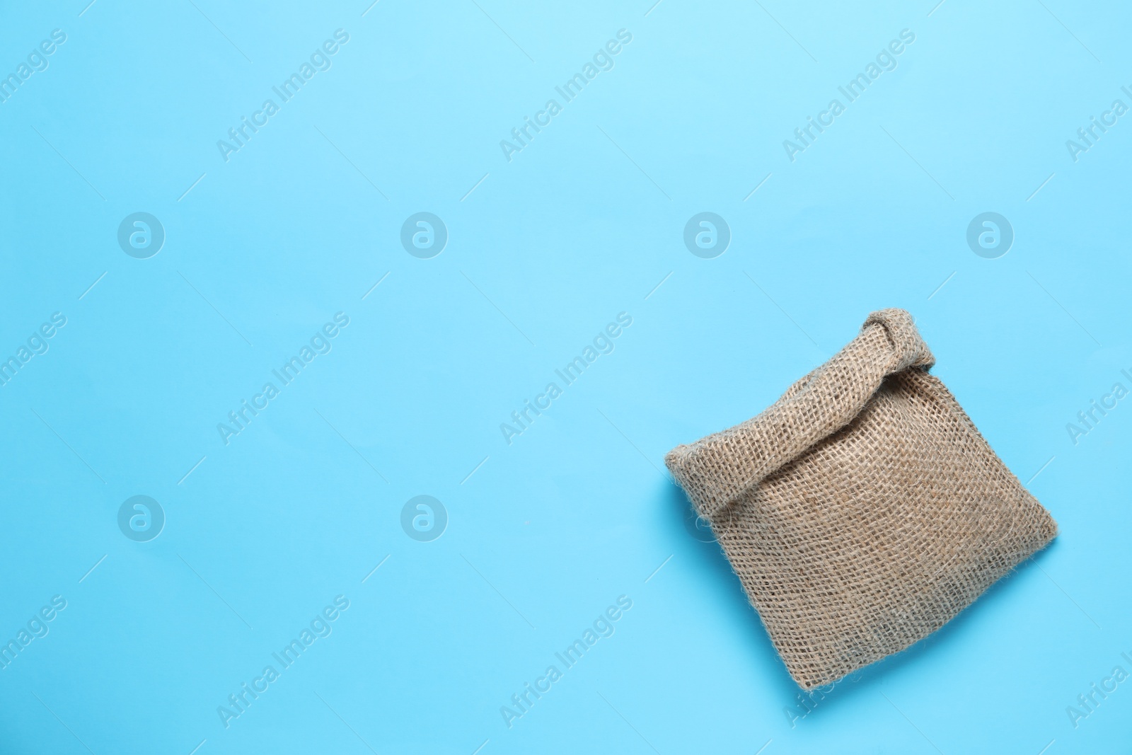 Photo of One burlap sack on light blue background, top view. Space for text