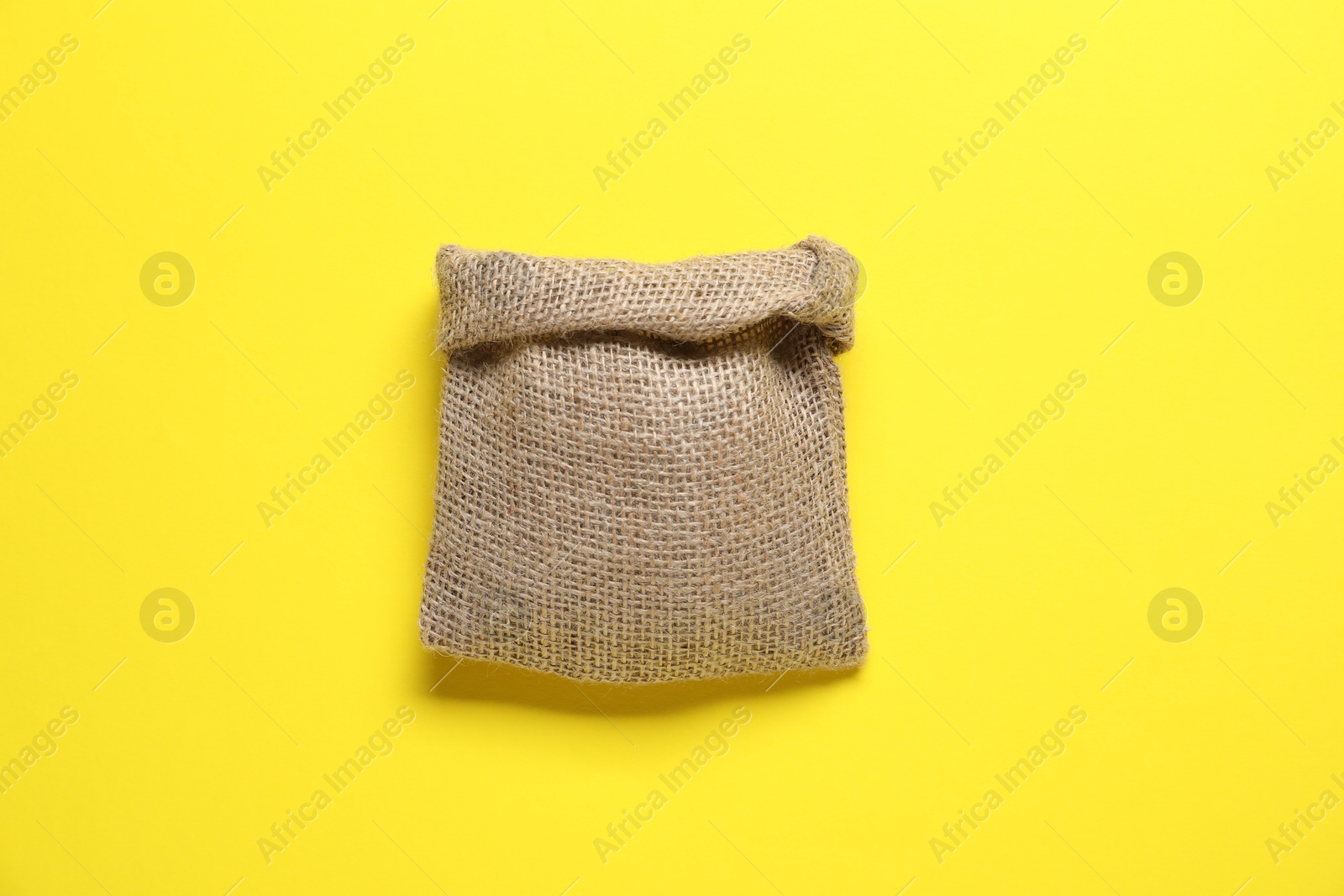 Photo of One burlap sack on yellow background, top view