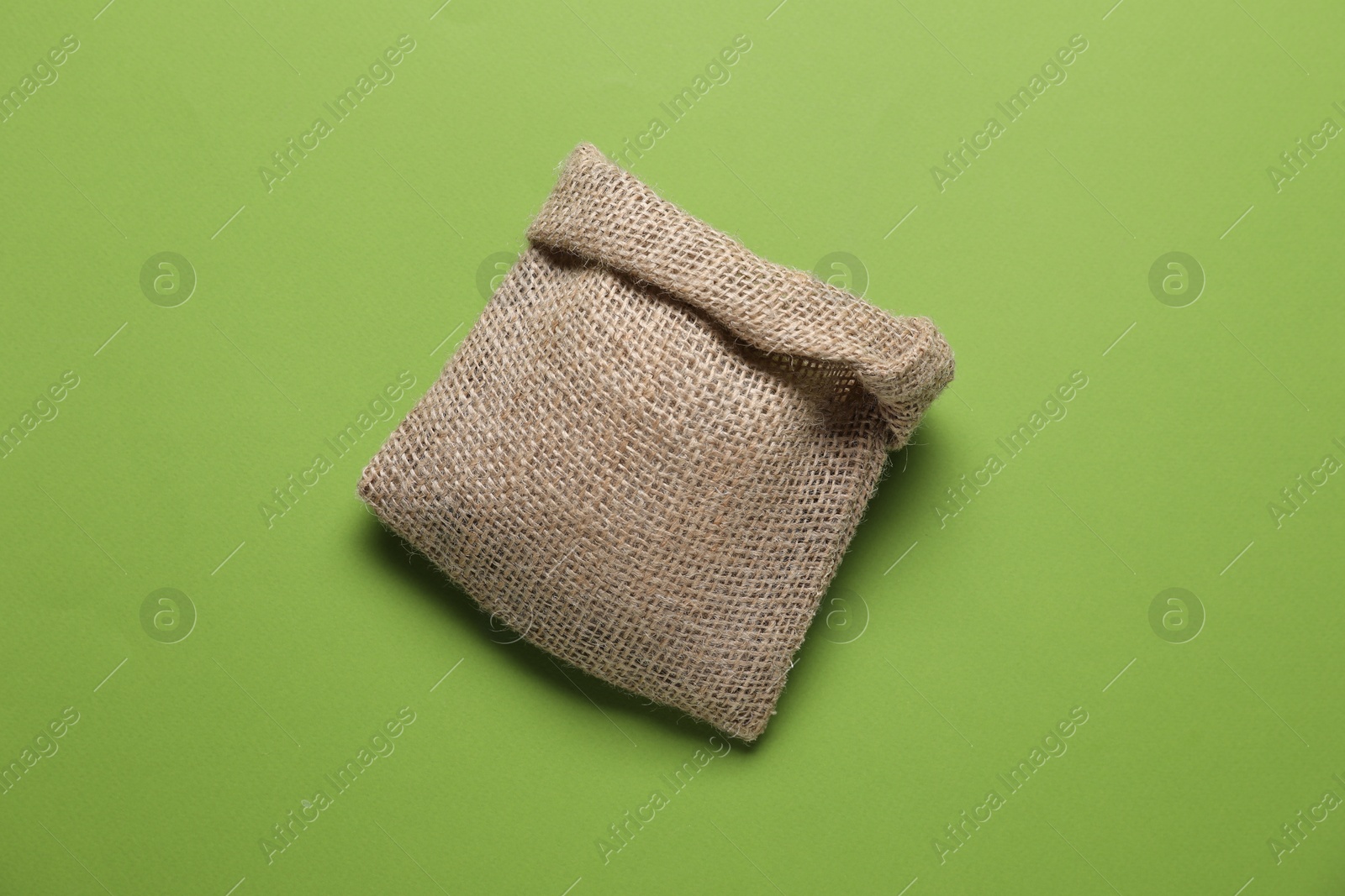 Photo of One burlap sack on light green background, top view