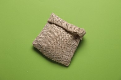 One burlap sack on light green background, top view