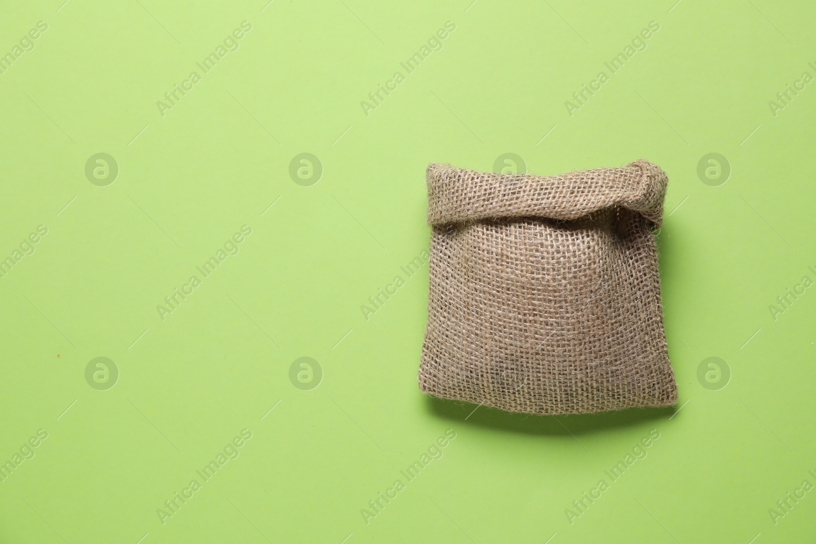 Photo of One burlap sack on light green background, top view. Space for text