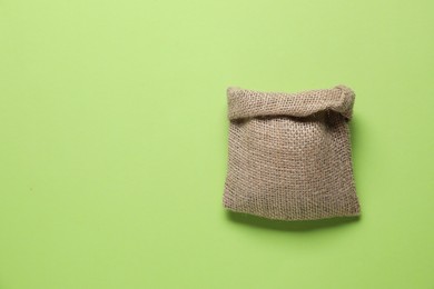 Photo of One burlap sack on light green background, top view. Space for text