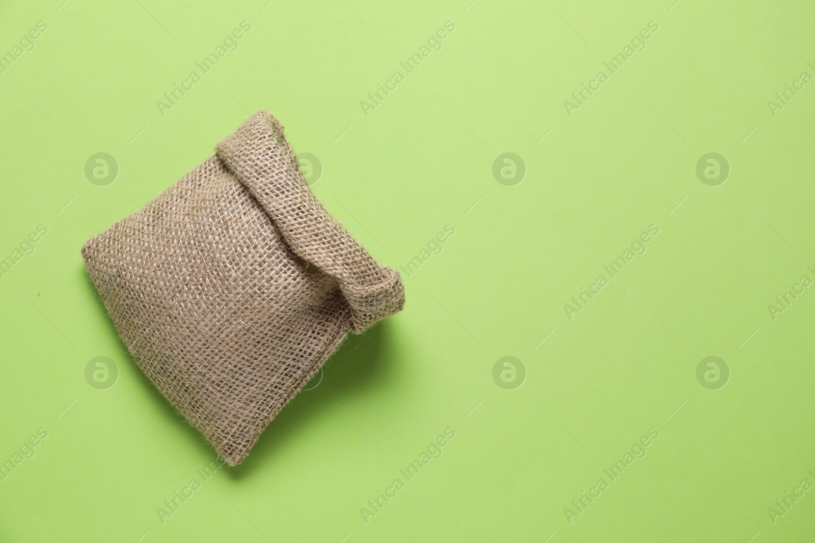 Photo of One burlap sack on light green background, top view. Space for text