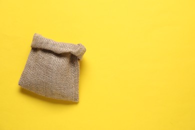 Photo of One burlap sack on yellow background, top view. Space for text