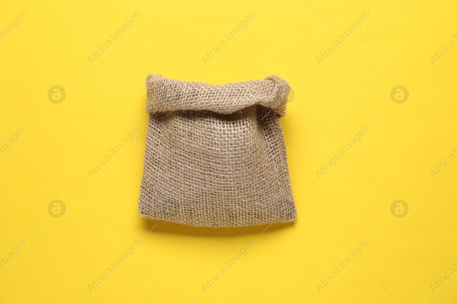 Photo of One burlap sack on yellow background, top view