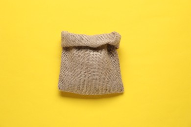 Photo of One burlap sack on yellow background, top view