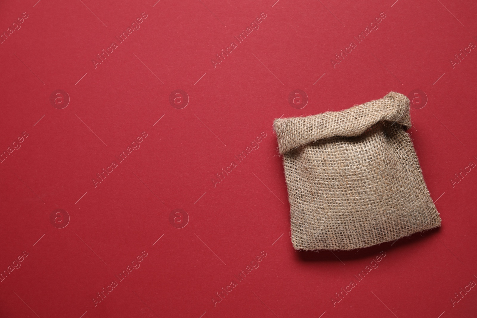 Photo of One burlap sack on red background, top view. Space for text