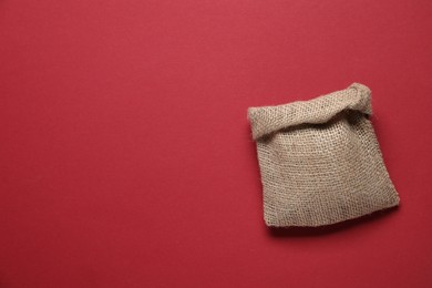 Photo of One burlap sack on red background, top view. Space for text