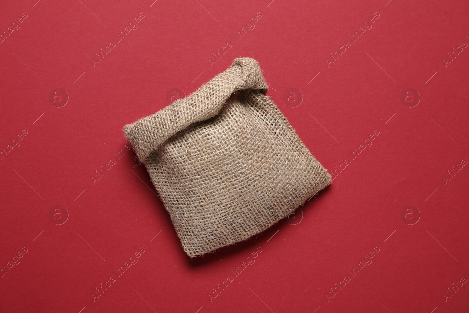 Photo of One burlap sack on red background, top view