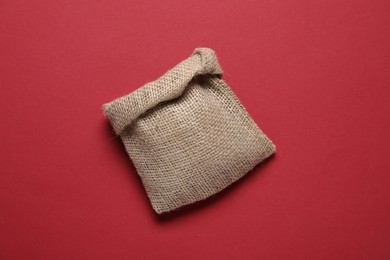 Photo of One burlap sack on red background, top view