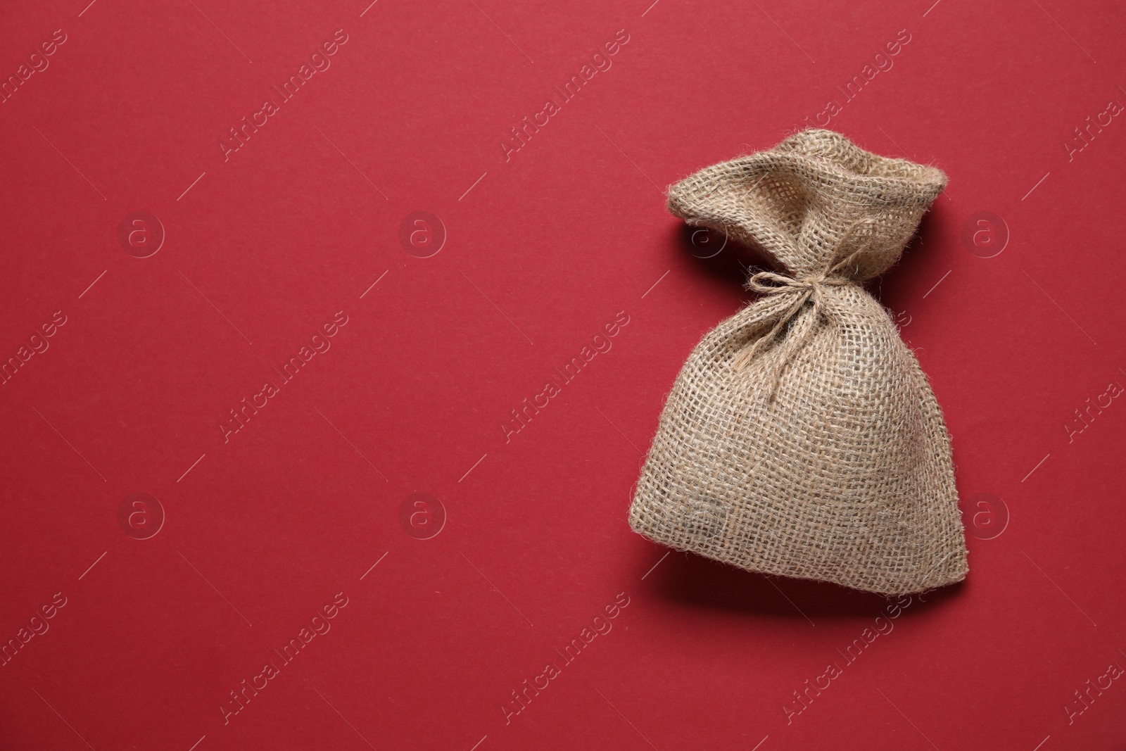 Photo of One burlap sack on red background, top view. Space for text