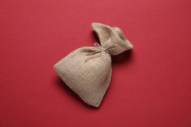 Photo of One burlap sack on red background, top view