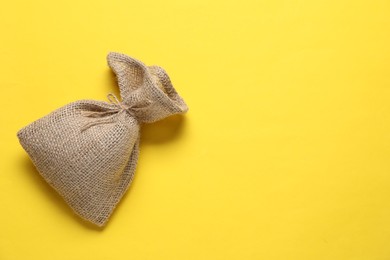 Photo of One burlap sack on yellow background, top view. Space for text