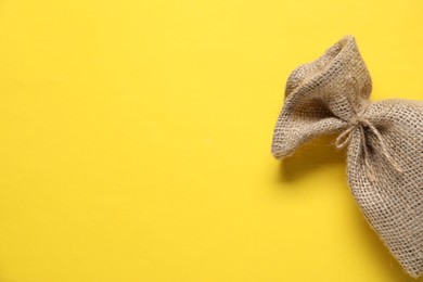 Photo of One burlap sack on yellow background, top view. Space for text