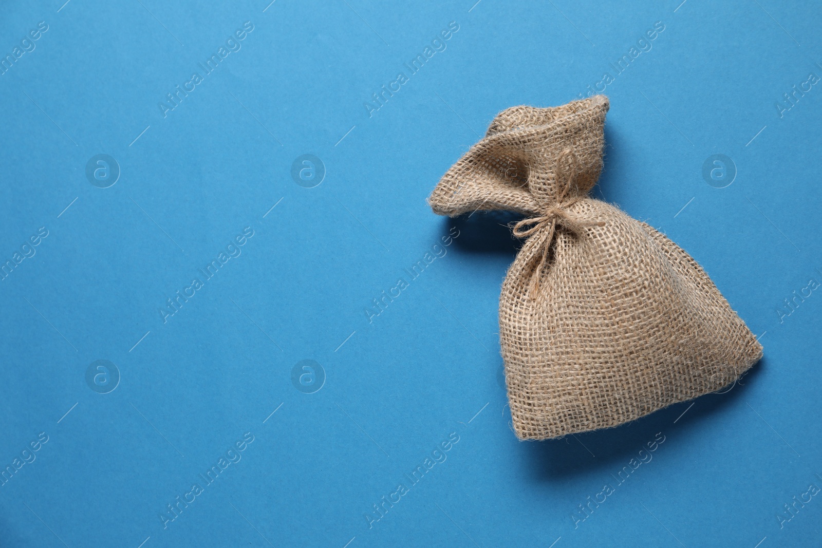 Photo of One burlap sack on light blue background, top view. Space for text