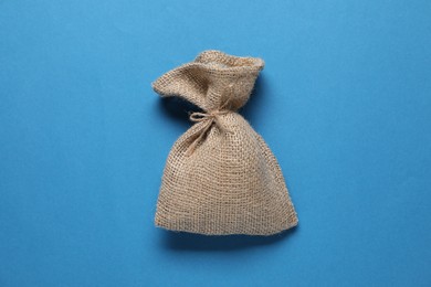 Photo of One burlap sack on light blue background, top view