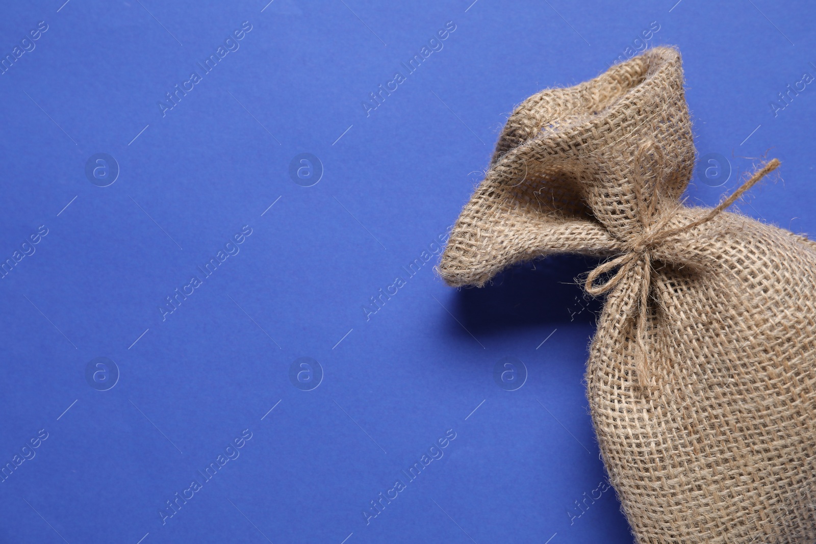 Photo of One burlap sack on blue background, top view. Space for text