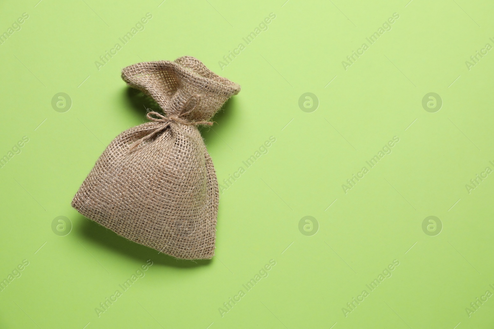 Photo of One burlap sack on green background, top view. Space for text