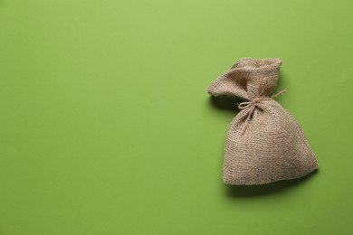 Photo of One burlap sack on green background, top view. Space for text