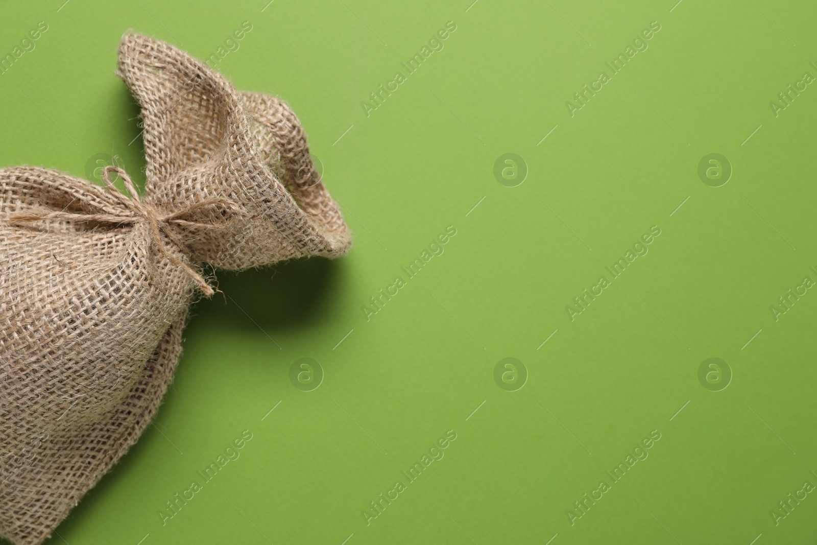 Photo of One burlap sack on green background, top view. Space for text