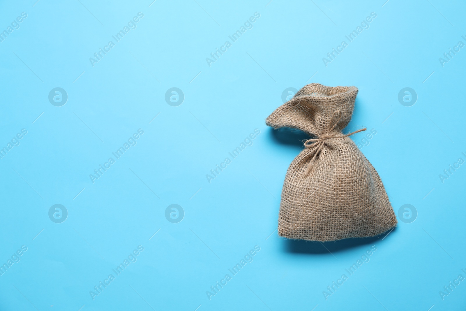 Photo of One burlap sack on light blue background, top view. Space for text