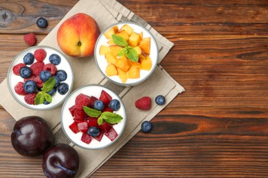 Photo of Tasty yogurt with fresh berries, fruits and mint in glasses on wooden table, flat lay. Space for text