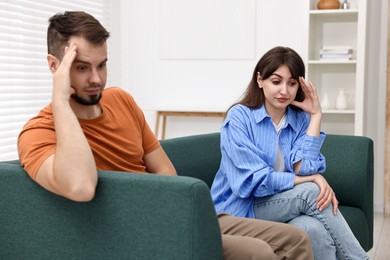 Photo of Embarrassed couple ignoring each other on sofa at home