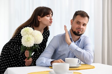 Bad date. Embarrassed man refusing from woman's kiss indoors