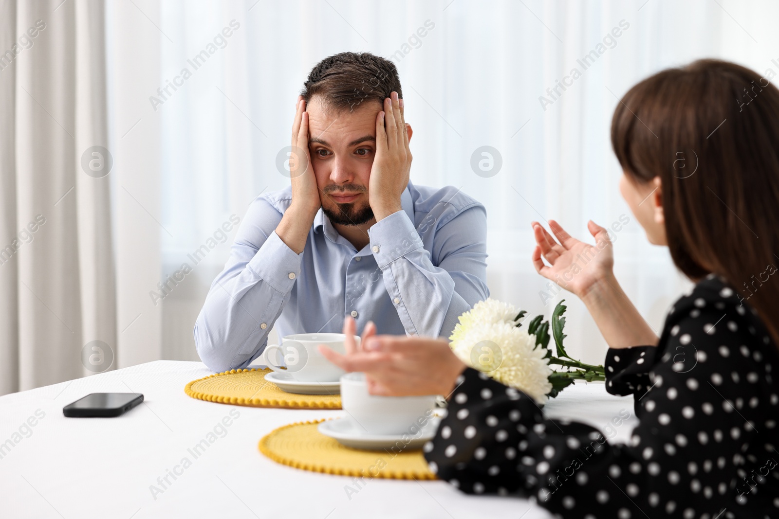 Photo of Embarrassing date. Obsessive woman talking to shocked man at table indoors