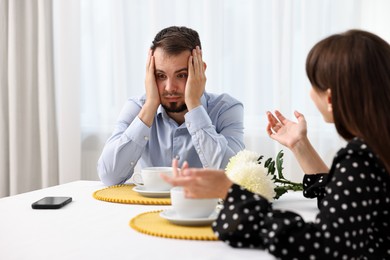 Embarrassing date. Obsessive woman talking to shocked man at table indoors