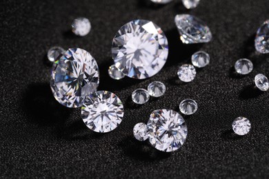 Photo of Many beautiful shiny diamonds on black fabric, closeup