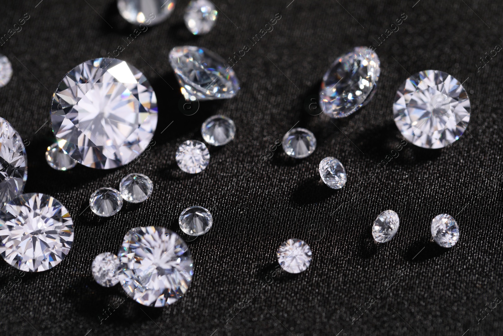 Photo of Many beautiful shiny diamonds on black fabric, closeup