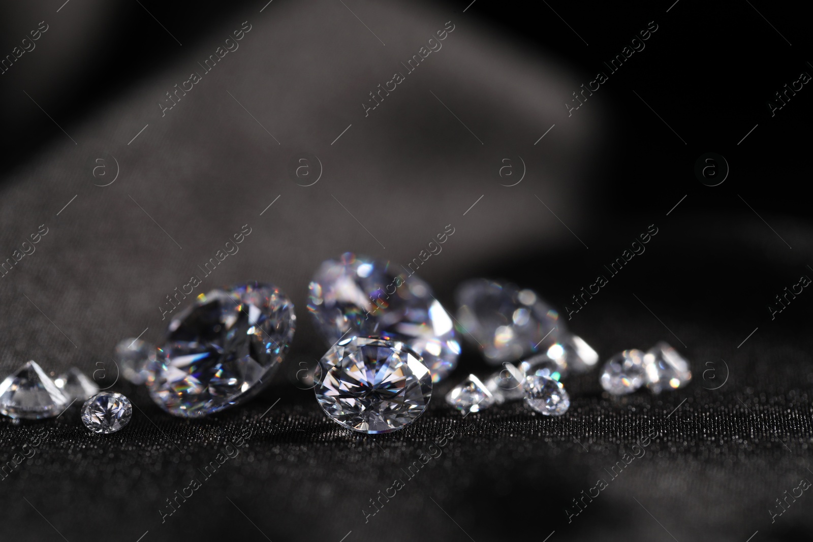 Photo of Many beautiful shiny diamonds on black fabric, closeup