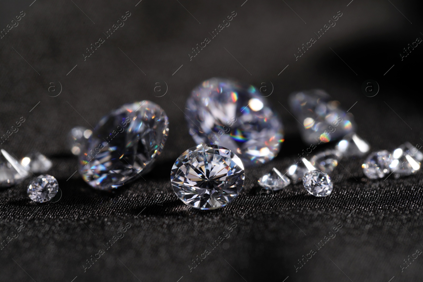 Photo of Many beautiful shiny diamonds on black fabric, closeup