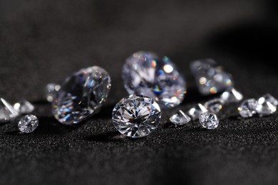 Many beautiful shiny diamonds on black fabric, closeup