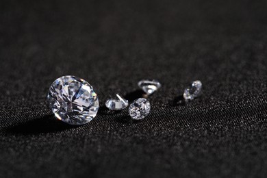 Photo of Many beautiful shiny diamonds on black fabric, closeup