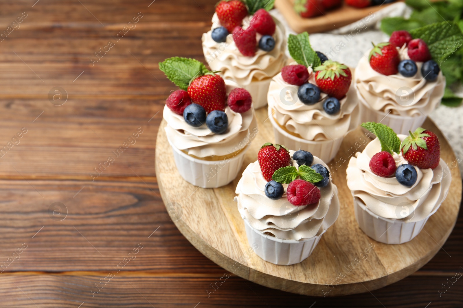 Photo of Tasty cupcakes with different berries and mint on wooden table, closeup. Space for text