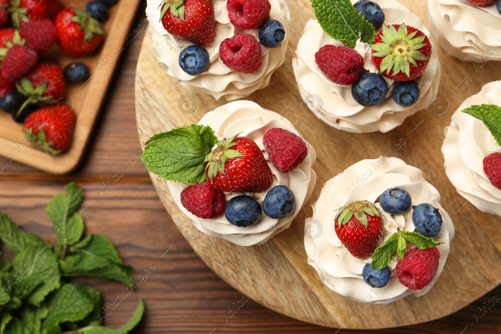 Photo of Tasty cupcakes with different berries and mint on wooden table, flat lay