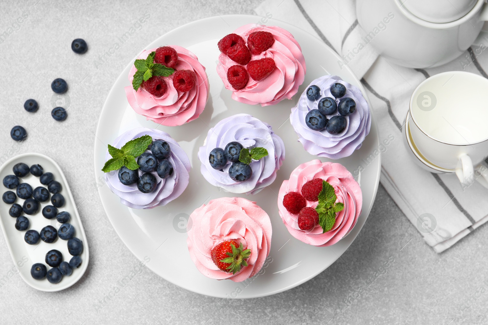 Photo of Tasty cupcakes with different berries on light grey table, flat lay