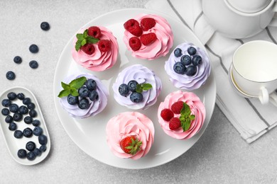 Photo of Tasty cupcakes with different berries on light grey table, flat lay