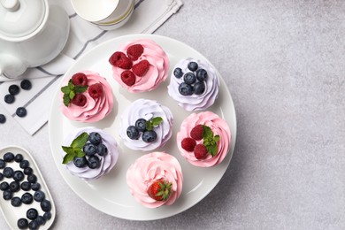 Photo of Tasty cupcakes with different berries on light grey table, flat lay. Space for text