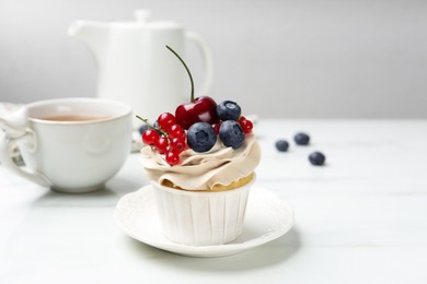 Photo of Tasty cupcake with different berries and tea on white marble table