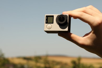 Man with modern action camera outdoors, closeup. Space for text