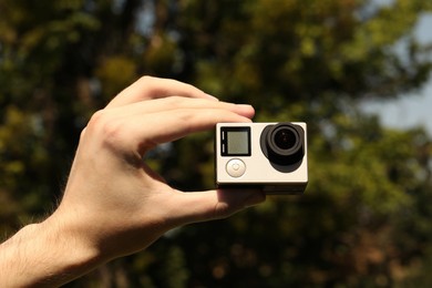 Photo of Man with modern action camera outdoors, closeup