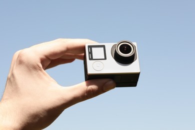 Photo of Man with modern action camera against blue sky, closeup